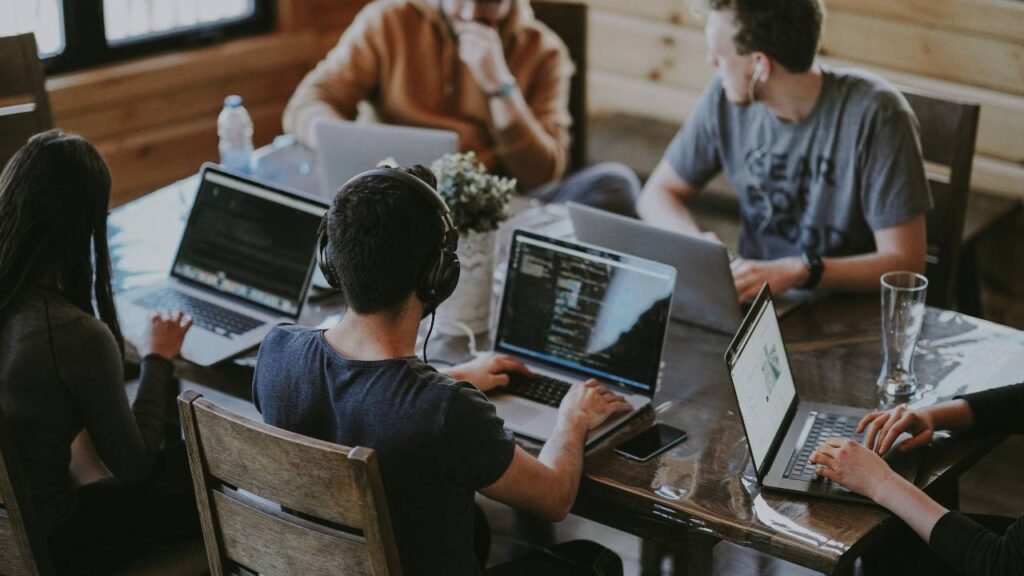 Several office workers using their laptops