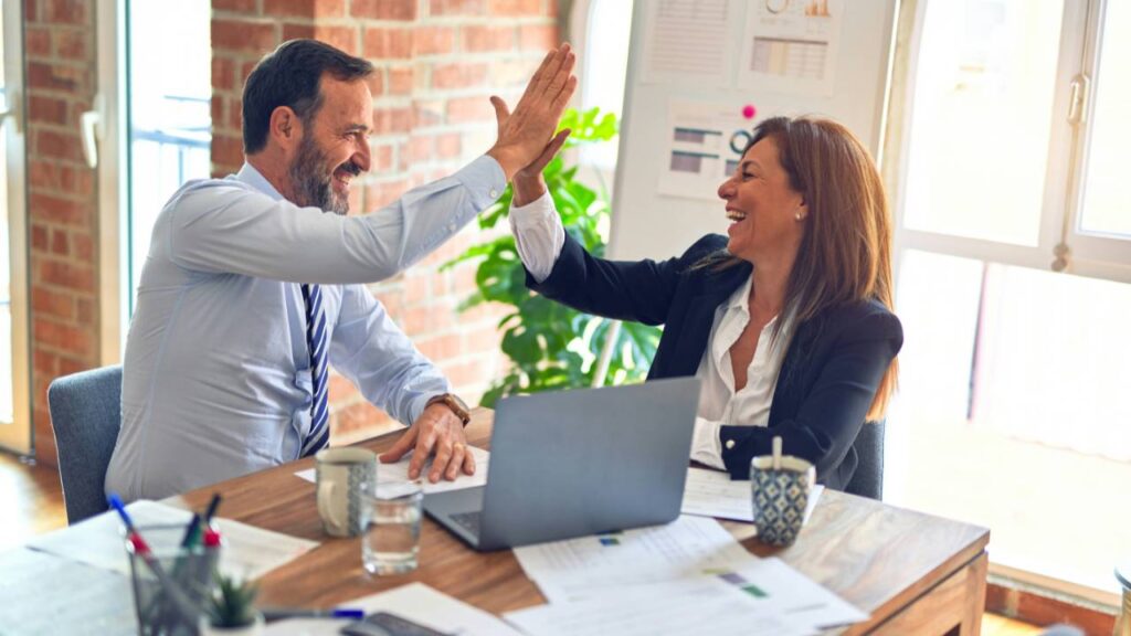 A woman and a man doing a "high five" at the office