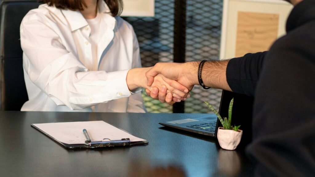 A woman and a man shaking hands over a table