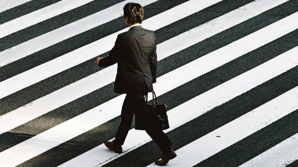 A photo of a businessman walking on a crosswalk