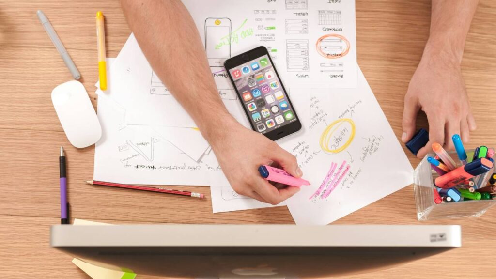 A man using a marker and some papers creating a business plan on his work desk