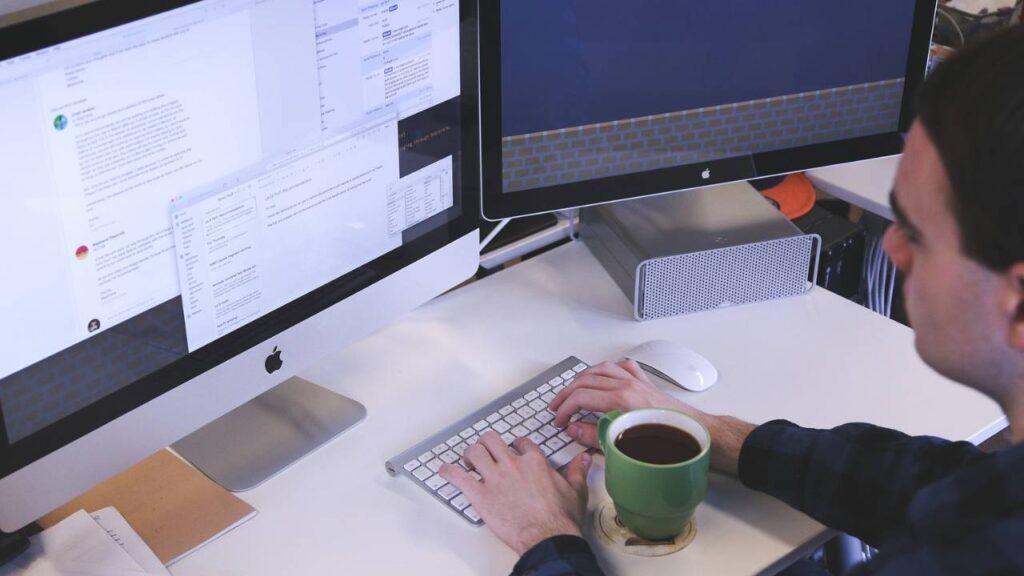 A man using an Apple desktop computer in the office