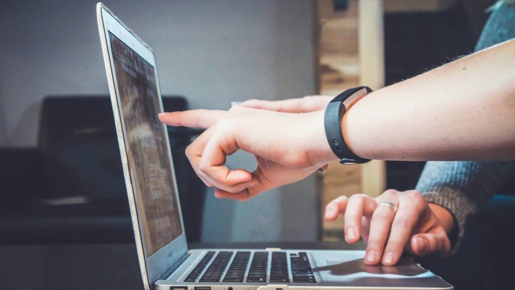 A person showing another person something on a laptop's display