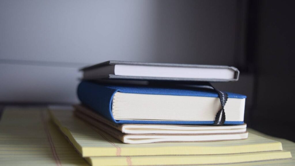 A stack of notebooks and thick books