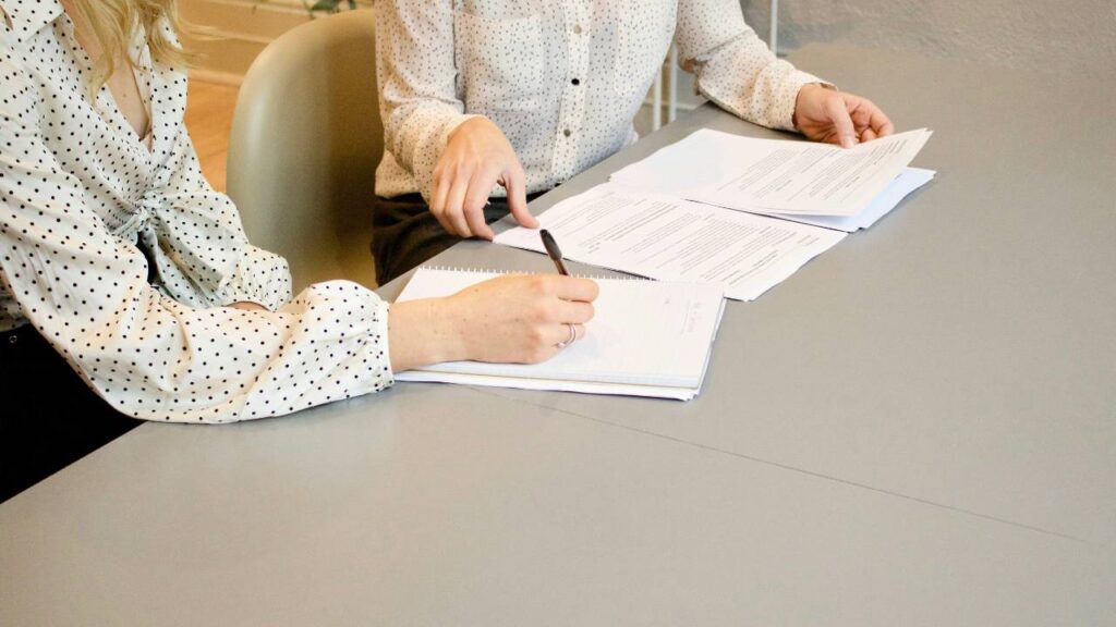 Two women signing documents