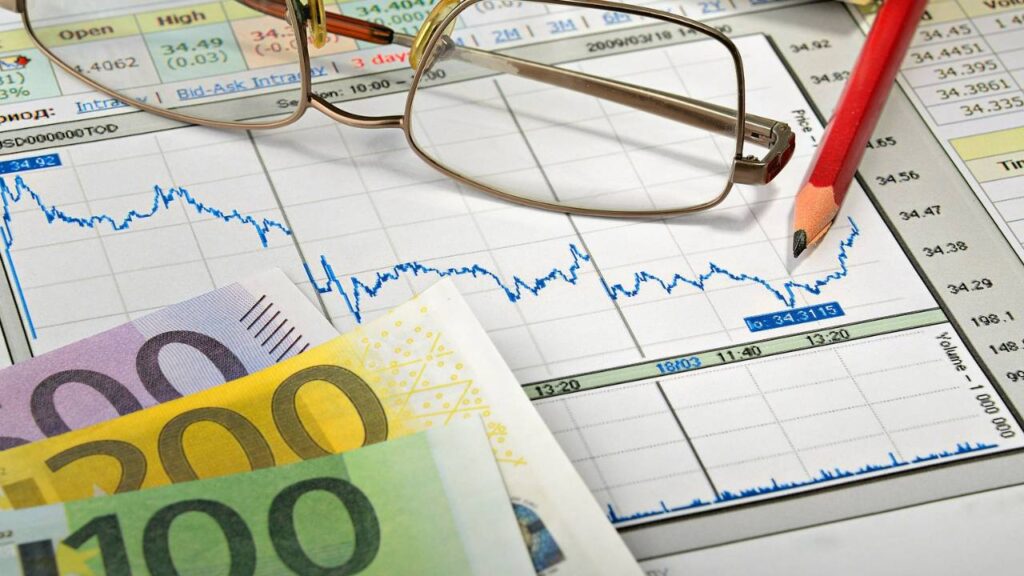 Several Euro bills placed on a document with financial charts 