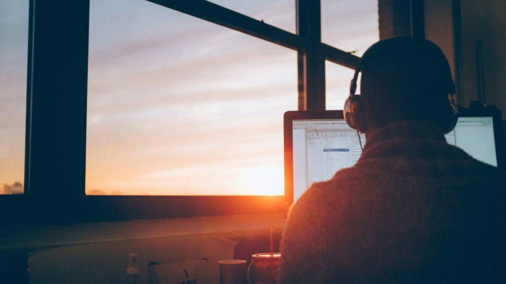 A man working on the computer with sunset in the background 