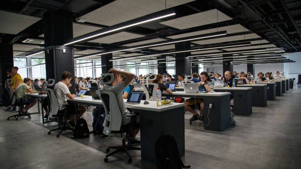 A photo of a large workspace with dozens of employees working on computers 